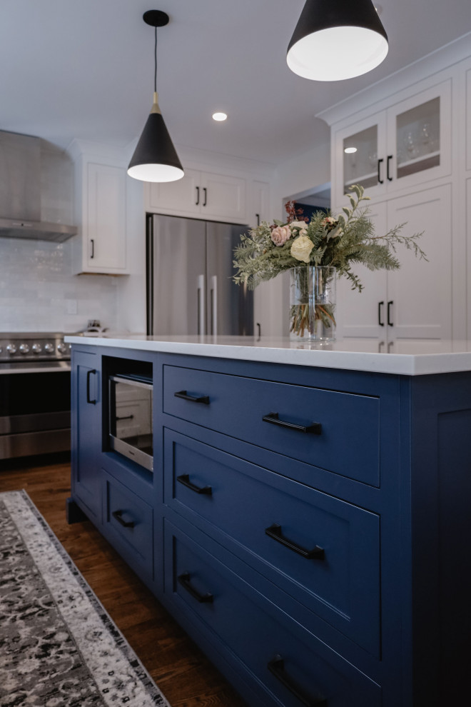 Eat-in kitchen - small transitional u-shaped medium tone wood floor and brown floor eat-in kitchen idea in Ottawa with an undermount sink, shaker cabinets, white cabinets, quartz countertops, white backsplash, subway tile backsplash, stainless steel appliances, an island and white countertops