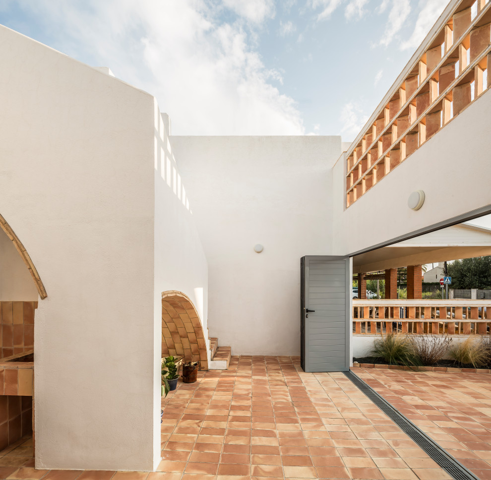 Ispirazione per un patio o portico mediterraneo di medie dimensioni e in cortile con scale, pavimentazioni in mattoni e un parasole