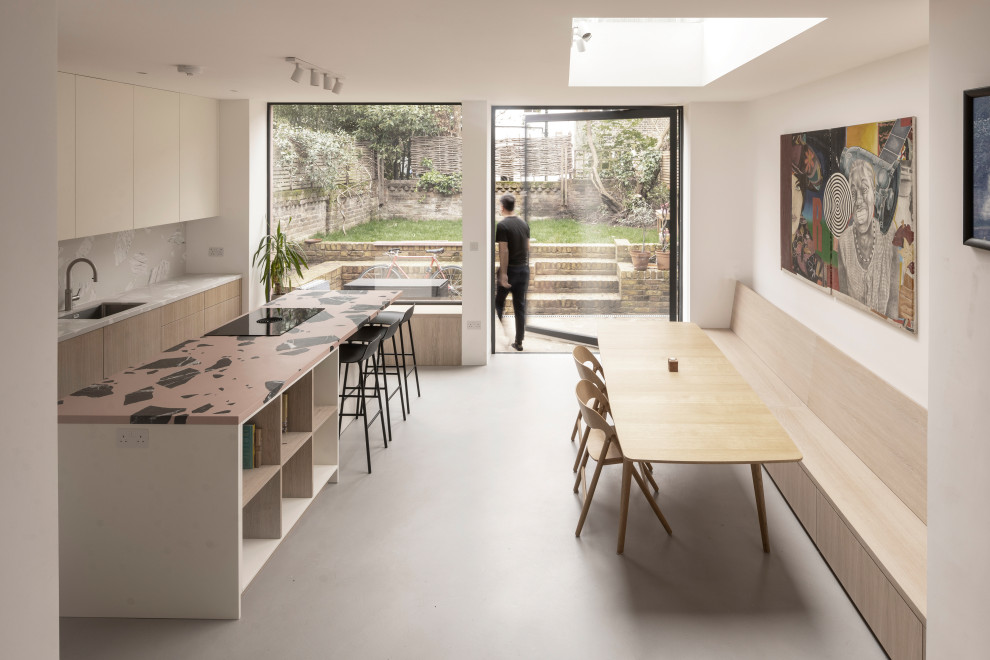Foto di una grande sala da pranzo aperta verso la cucina contemporanea con pareti bianche, pavimento in cemento e pavimento grigio