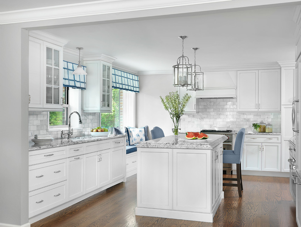 Mid-sized elegant u-shaped medium tone wood floor and brown floor enclosed kitchen photo in St Louis with white cabinets, granite countertops, gray backsplash, stainless steel appliances, an island, an undermount sink, shaker cabinets, subway tile backsplash and gray countertops