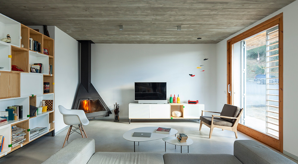 Design ideas for a large modern open concept living room in Barcelona with a library, white walls, concrete floors, a corner fireplace and a freestanding tv.