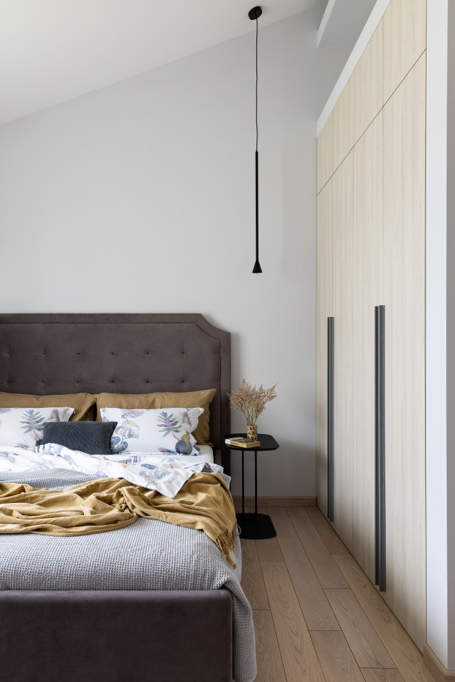 На фото: гостевая спальня среднего размера, (комната для гостей), в светлых тонах в современном стиле с белыми стенами, паркетным полом среднего тона и коричневым полом