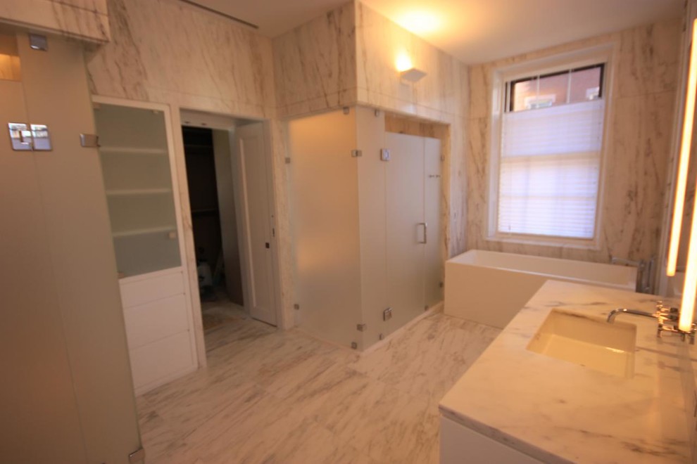 Design ideas for a mid-sized contemporary master bathroom in Boston with an undermount sink, flat-panel cabinets, white cabinets, marble benchtops, a corner tub, a corner shower, a two-piece toilet, white tile, stone tile, white walls and ceramic floors.