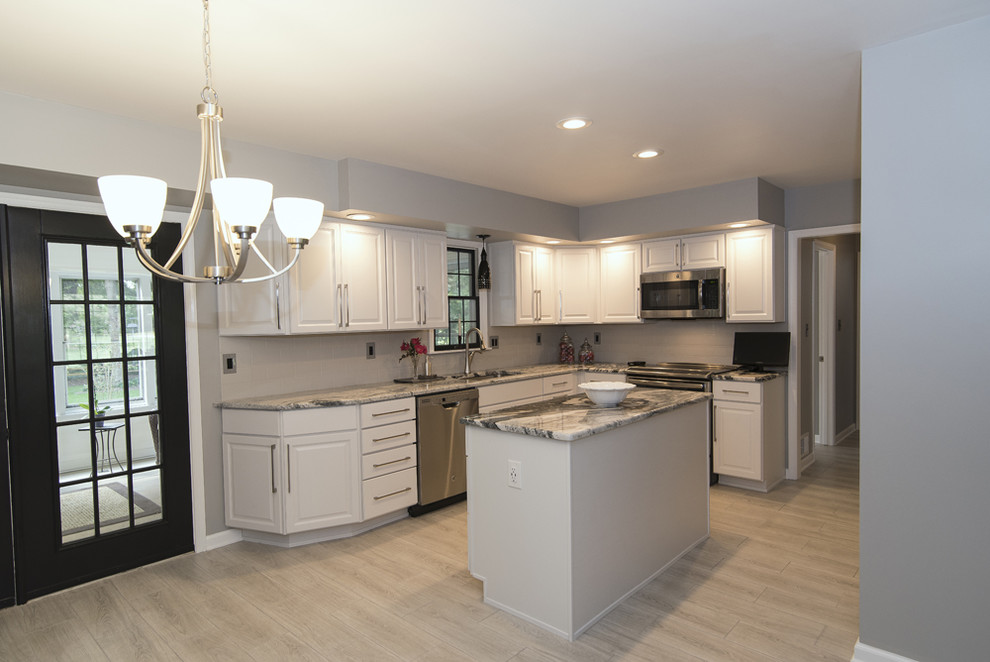 Inspiration for a mid-sized contemporary u-shaped eat-in kitchen in Baltimore with an undermount sink, raised-panel cabinets, white cabinets, granite benchtops, white splashback, ceramic splashback, stainless steel appliances, ceramic floors, with island and grey floor.