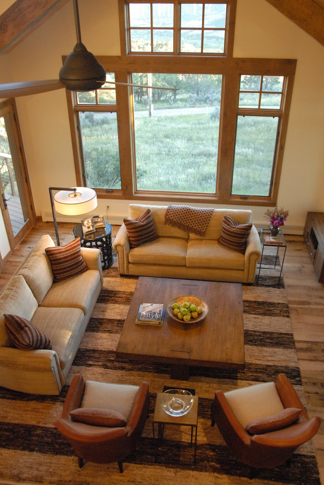 This is an example of a mid-sized transitional formal open concept living room in Denver with beige walls, medium hardwood floors, a two-sided fireplace, a tile fireplace surround, a wall-mounted tv and brown floor.