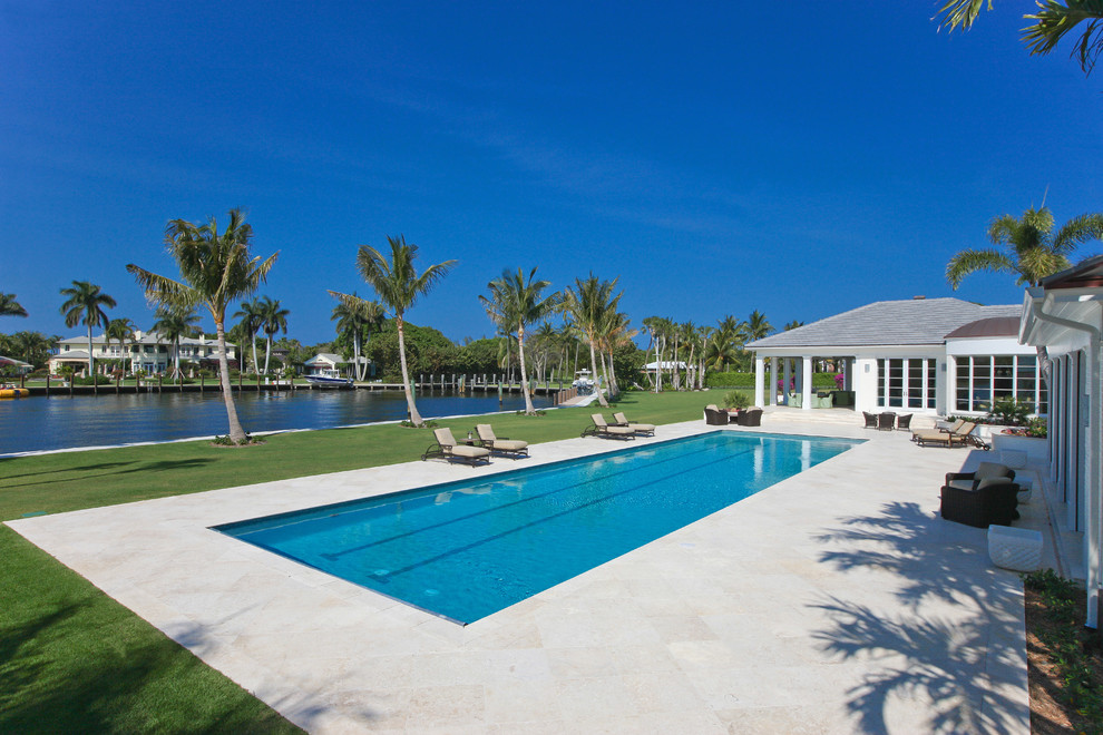 Expansive contemporary backyard rectangular lap pool in Miami with a pool house and tile.