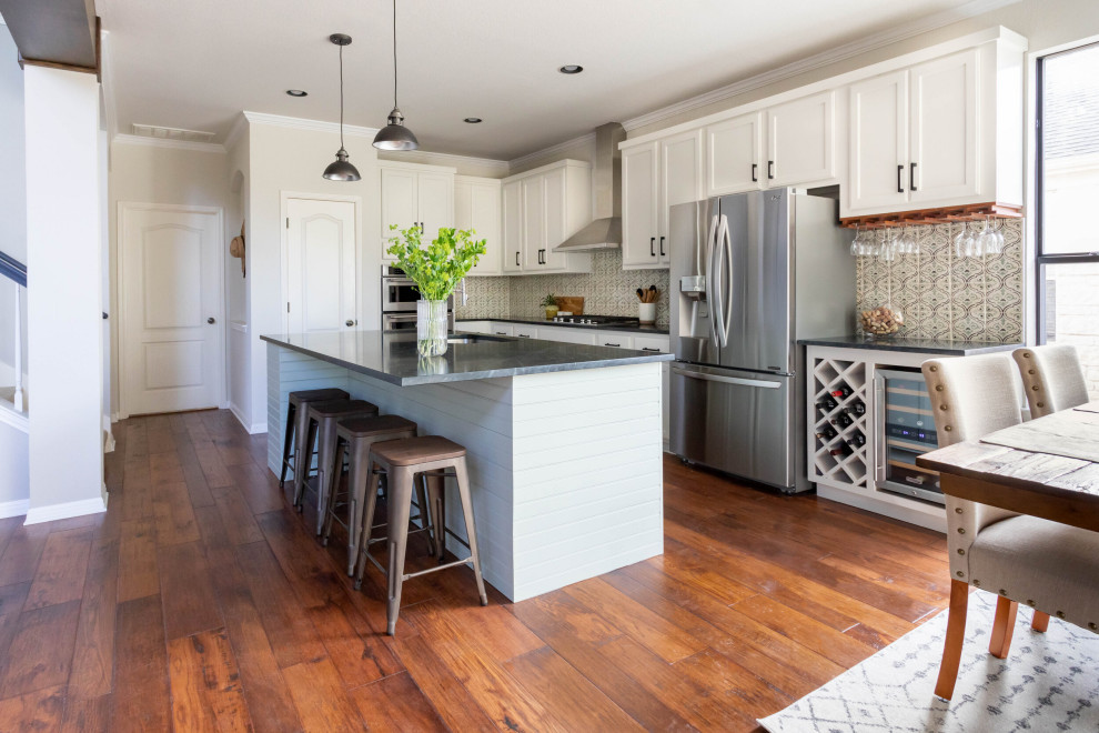 Eat-in kitchen - mid-sized transitional l-shaped medium tone wood floor and brown floor eat-in kitchen idea in Austin with an undermount sink, shaker cabinets, white cabinets, soapstone countertops, beige backsplash, ceramic backsplash, stainless steel appliances, an island and black countertops