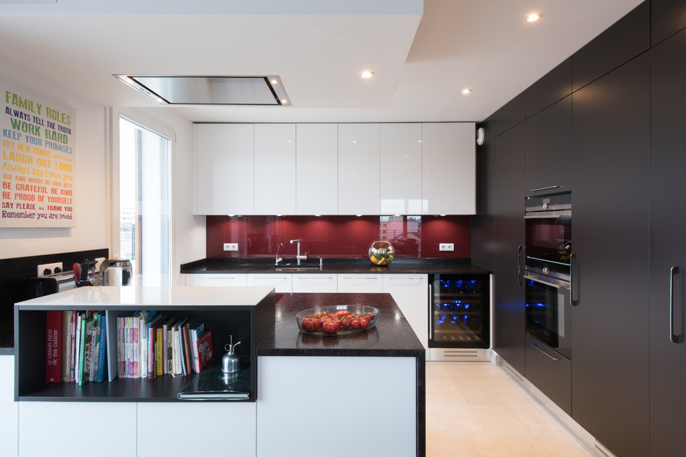 Photo of a large contemporary u-shaped open plan kitchen in Paris with red splashback, an undermount sink, flat-panel cabinets, glass sheet splashback, a peninsula, ceramic floors and panelled appliances.
