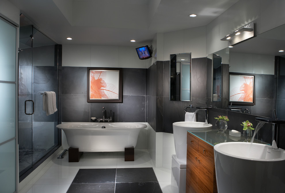 Inspiration for a large contemporary master bathroom in Miami with a pedestal sink, flat-panel cabinets, medium wood cabinets, a freestanding tub, gray tile, glass benchtops and marble floors.