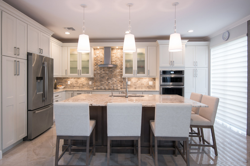 This is an example of a large transitional l-shaped open plan kitchen in Miami with an undermount sink, shaker cabinets, white cabinets, granite benchtops, beige splashback, stone tile splashback, stainless steel appliances and with island.