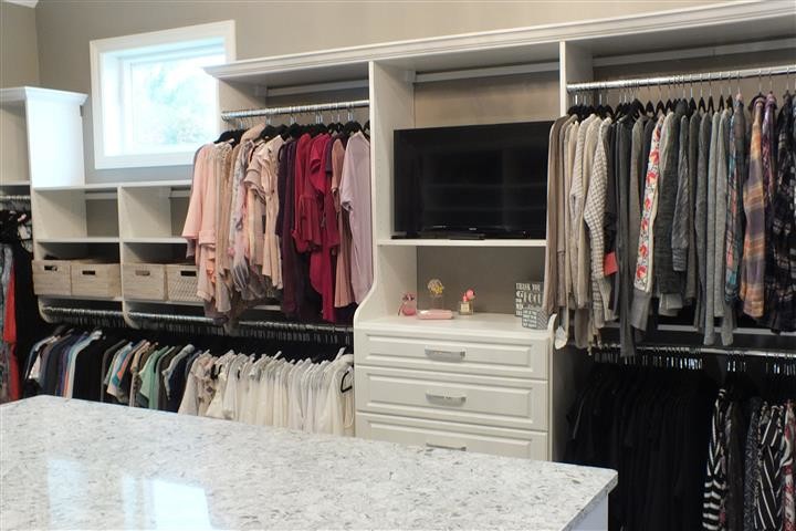 Inspiration for an expansive contemporary gender-neutral walk-in wardrobe in Cleveland with raised-panel cabinets, white cabinets and vinyl floors.