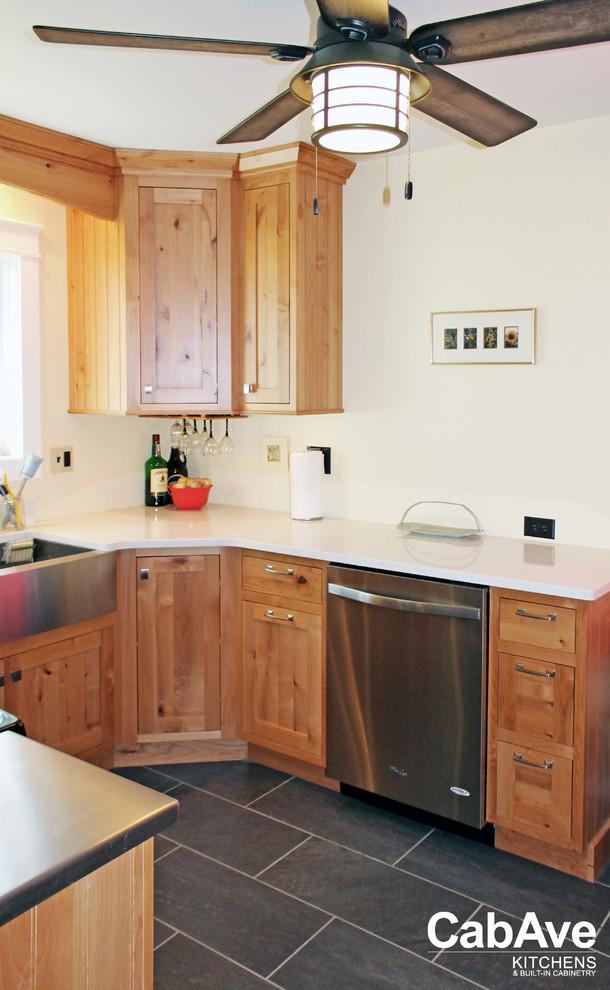 Example of a small mountain style u-shaped slate floor and gray floor enclosed kitchen design with a farmhouse sink, recessed-panel cabinets, medium tone wood cabinets, quartz countertops, stainless steel appliances and no island