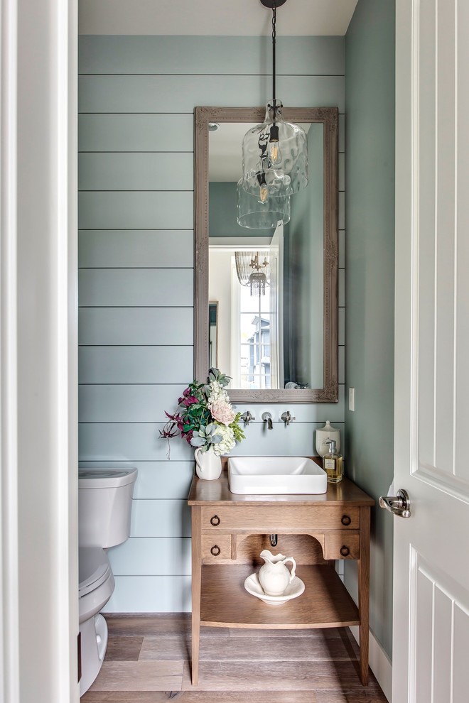 This is an example of a powder room in Calgary with blue walls, furniture-like cabinets, medium wood cabinets, medium hardwood floors, a vessel sink, wood benchtops, brown floor and brown benchtops.