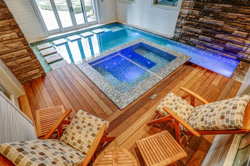 Photo of a small eclectic indoor rectangular pool in Toronto with a hot tub and decking.