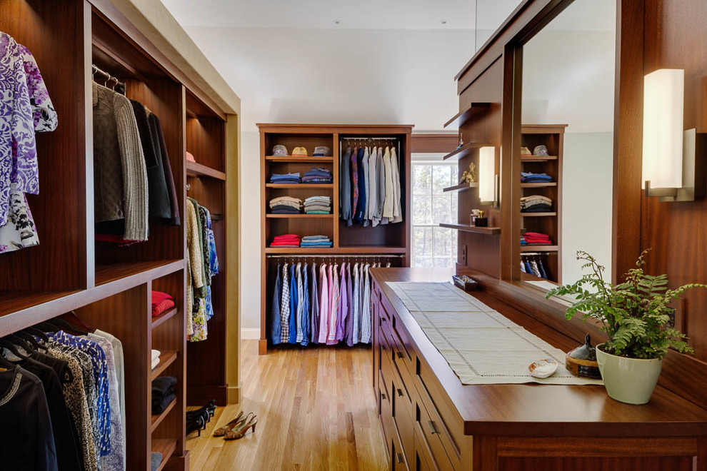Photo of a large traditional gender-neutral dressing room in Boston with shaker cabinets, medium wood cabinets and light hardwood floors.