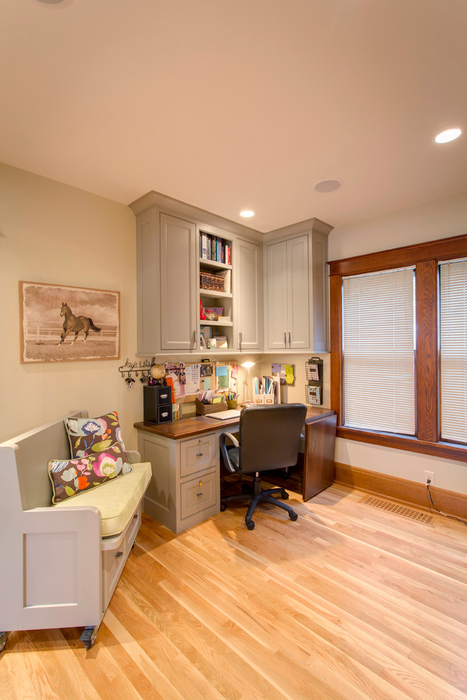 This is an example of a mid-sized transitional home office in Other with medium hardwood floors, a built-in desk and beige walls.