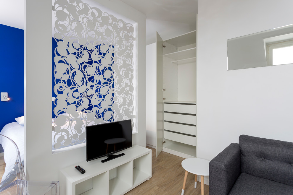 Cette image montre un petit salon mansardé ou avec mezzanine design avec une salle de réception, un mur blanc, parquet clair, aucune cheminée, un téléviseur indépendant et un sol beige.