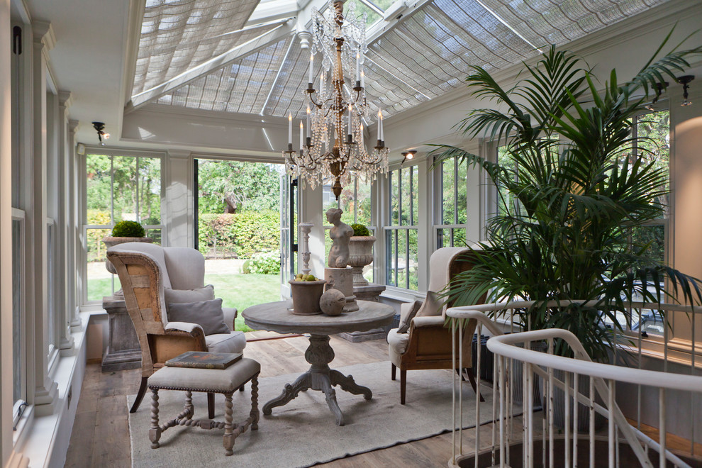 Design ideas for a large traditional sunroom in London with medium hardwood floors, a standard fireplace, a stone fireplace surround and a skylight.