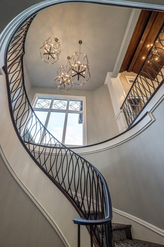 This is an example of an expansive transitional carpeted curved staircase in Cincinnati with carpet risers and metal railing.