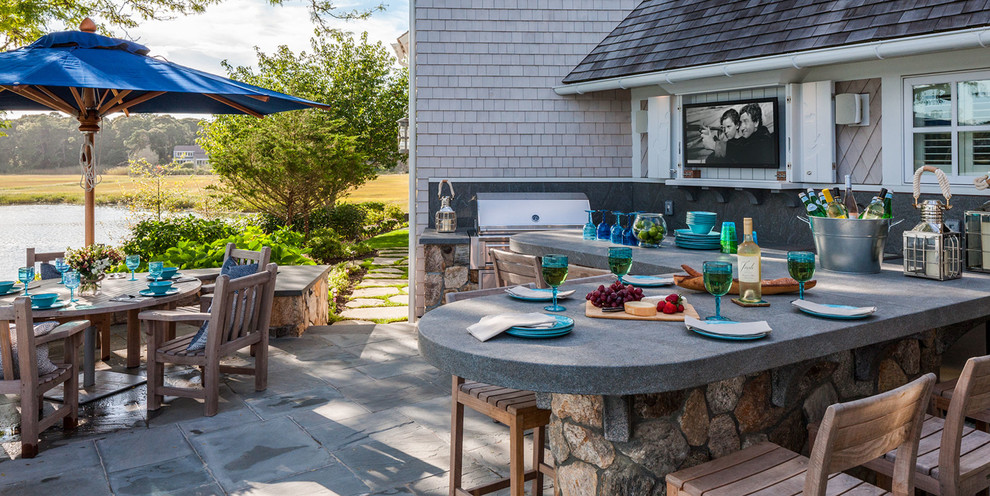 This is an example of a mid-sized beach style backyard patio in Boston with an outdoor kitchen, natural stone pavers and no cover.