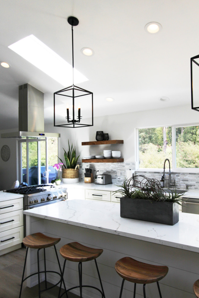 Example of a mid-sized transitional l-shaped vinyl floor, brown floor and vaulted ceiling eat-in kitchen design with an undermount sink, shaker cabinets, white cabinets, quartz countertops, multicolored backsplash, mosaic tile backsplash, stainless steel appliances, an island and white countertops