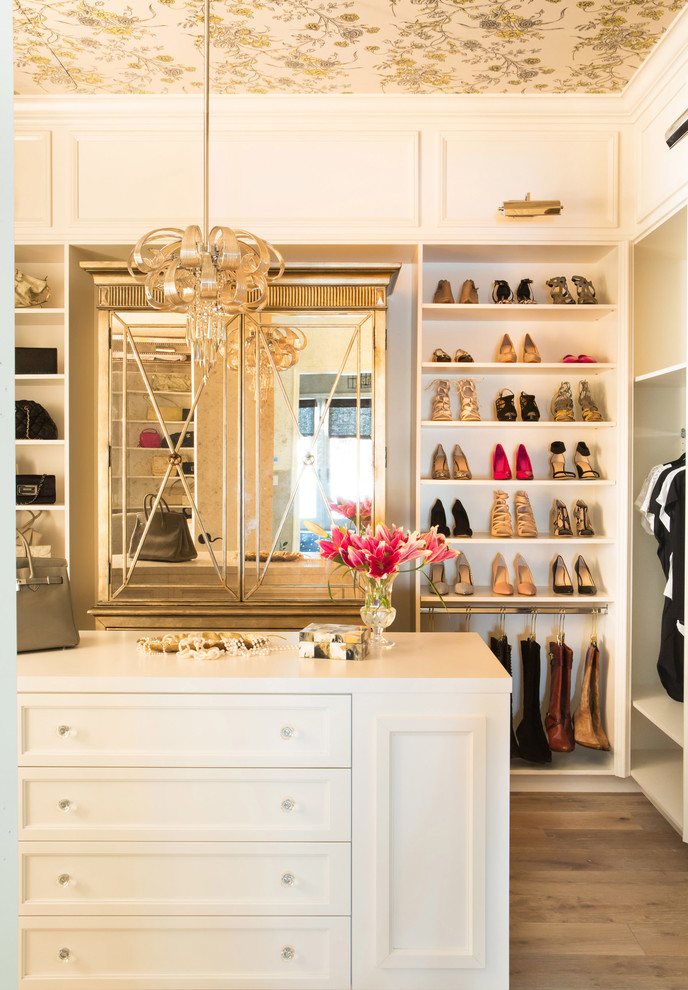 This is an example of a large transitional women's walk-in wardrobe in San Diego with white cabinets, medium hardwood floors and recessed-panel cabinets.