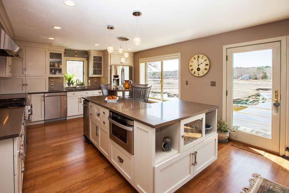 Eat-in kitchen - large transitional l-shaped medium tone wood floor eat-in kitchen idea in Boston with an undermount sink, shaker cabinets, white cabinets, quartz countertops, gray backsplash, glass sheet backsplash, stainless steel appliances and an island