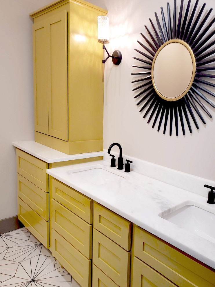 На фото: главная ванная комната среднего размера в стиле фьюжн с фасадами в стиле шейкер, желтыми фасадами, двойным душем, унитазом-моноблоком, белой плиткой, керамической плиткой, серыми стенами, полом из керамической плитки, врезной раковиной, мраморной столешницей, белым полом, душем с распашными дверями, белой столешницей, сиденьем для душа, тумбой под две раковины и напольной тумбой