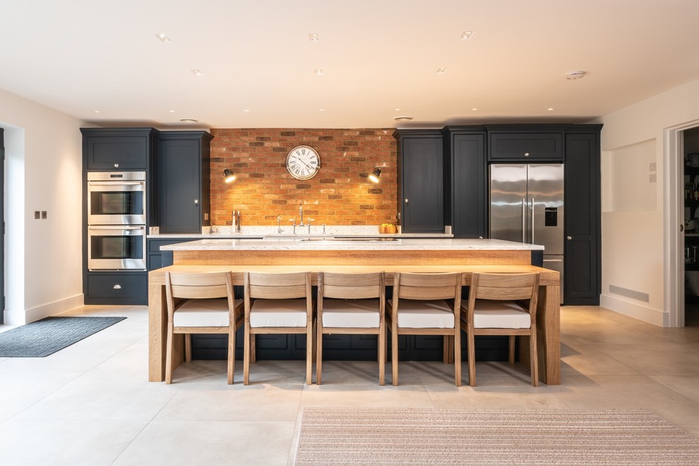 Design ideas for an expansive contemporary single-wall open plan kitchen in Essex with a farmhouse sink, beaded inset cabinets, blue cabinets, quartzite benchtops, multi-coloured splashback, brick splashback, stainless steel appliances, terra-cotta floors, with island, beige floor and white benchtop.