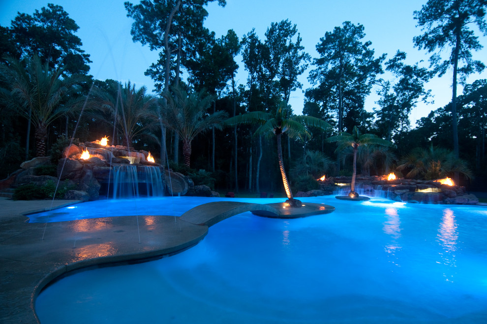 Expansive tropical backyard custom-shaped lap pool in Houston with stamped concrete and a water feature.