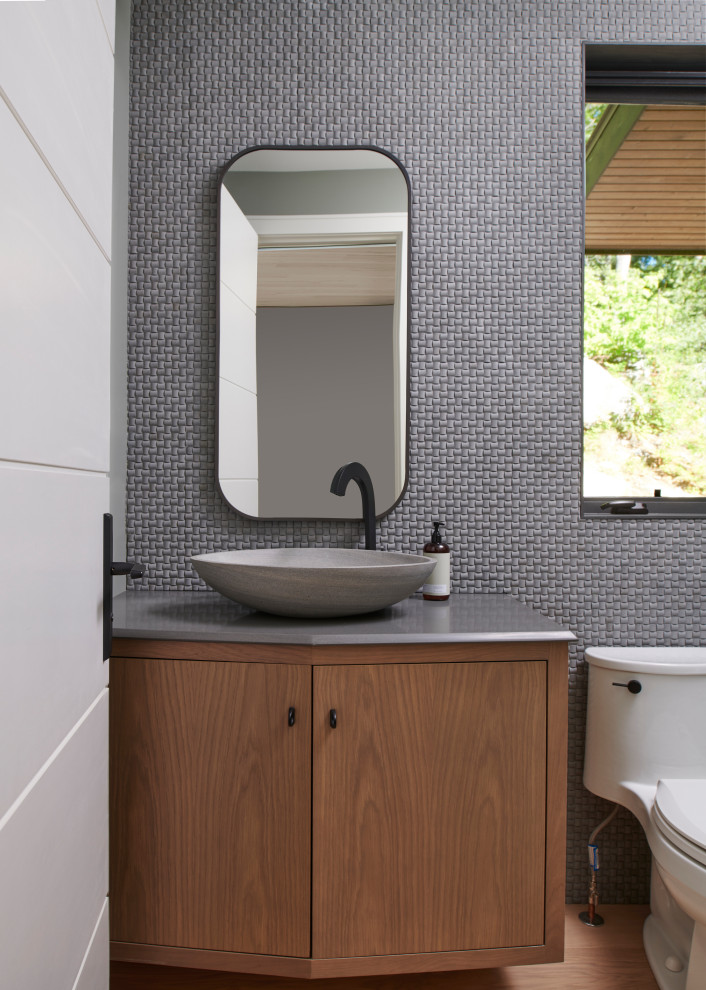 Cette photo montre un petit WC et toilettes tendance en bois brun avec un placard à porte plane, WC à poser, un mur gris, un plan de toilette gris et meuble-lavabo suspendu.