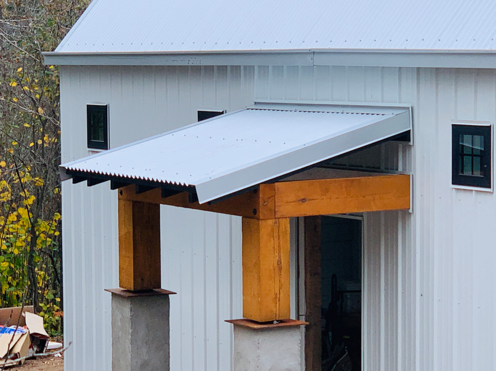 Immagine di un piccolo portico country dietro casa con lastre di cemento, un tetto a sbalzo e parapetto in legno