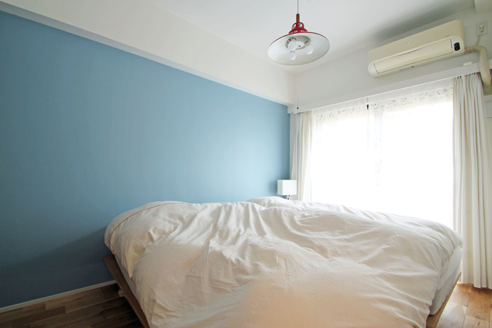 Modelo de dormitorio principal nórdico con paredes azules, suelo de madera en tonos medios y suelo beige