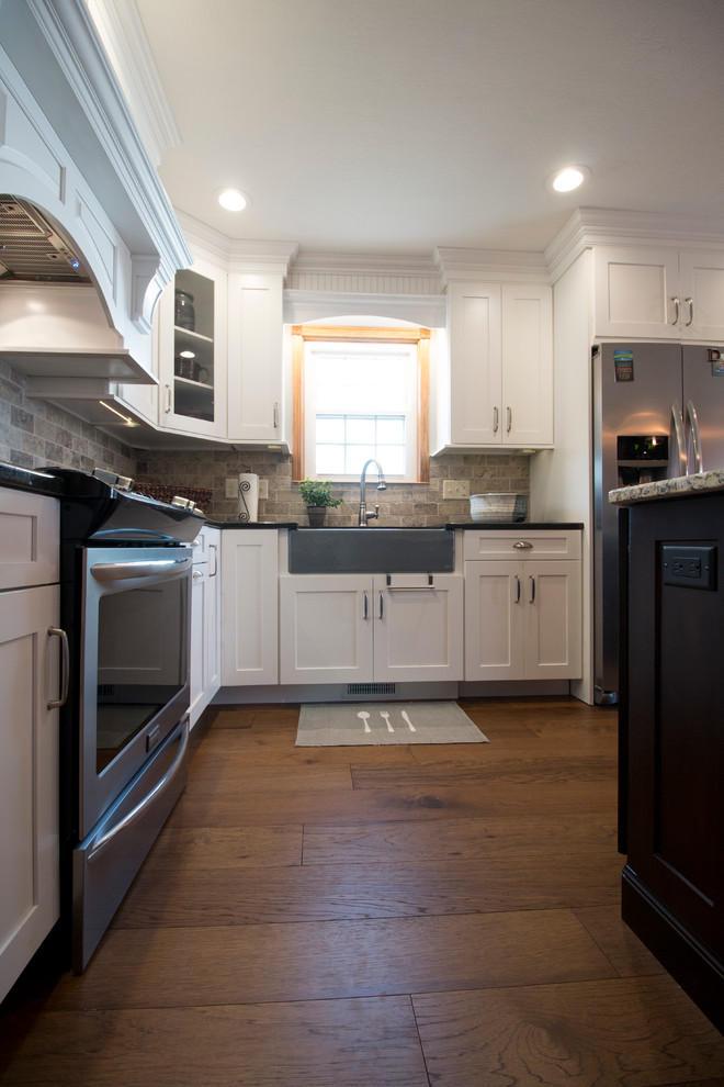 Eat-in kitchen - large transitional l-shaped medium tone wood floor eat-in kitchen idea with an undermount sink, shaker cabinets, white cabinets, granite countertops, gray backsplash, stone tile backsplash, stainless steel appliances and an island