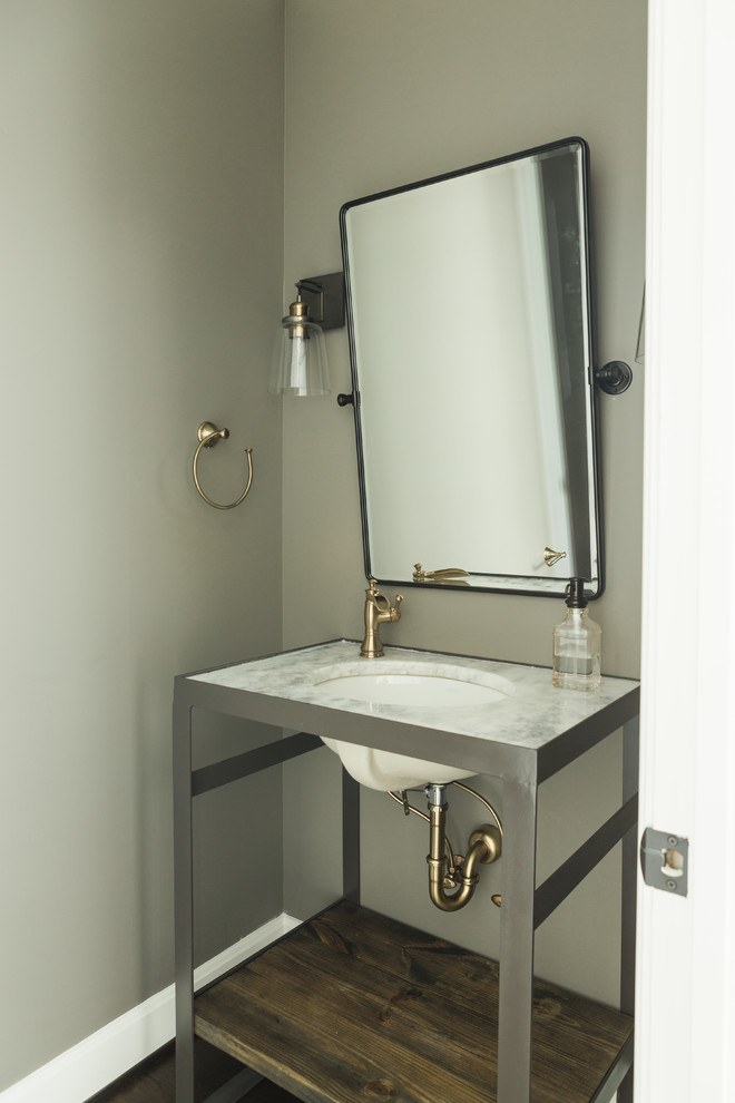 Mid-sized transitional powder room in Nashville with furniture-like cabinets, grey cabinets, gray tile, grey walls, dark hardwood floors, an undermount sink, marble benchtops and brown floor.