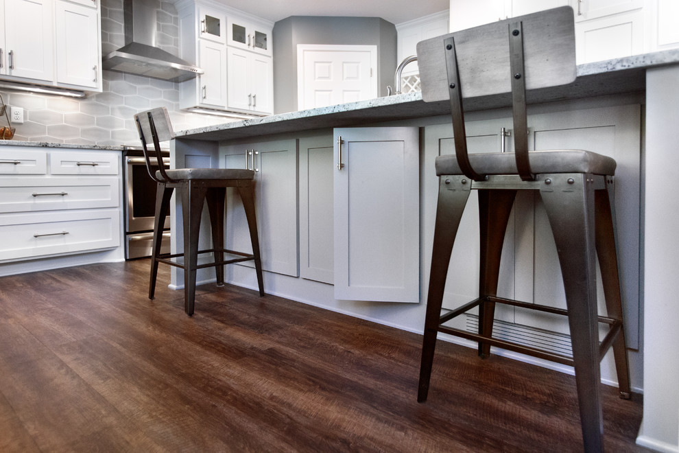 Eat-in kitchen - mid-sized transitional l-shaped vinyl floor and brown floor eat-in kitchen idea in Minneapolis with an undermount sink, shaker cabinets, white cabinets, granite countertops, gray backsplash, ceramic backsplash, stainless steel appliances, an island and multicolored countertops