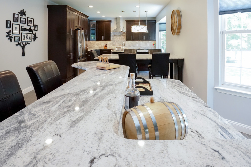 Eat-in kitchen - large transitional l-shaped vinyl floor and brown floor eat-in kitchen idea in Philadelphia with a double-bowl sink, granite countertops, gray backsplash, stone tile backsplash, stainless steel appliances, an island, shaker cabinets and dark wood cabinets