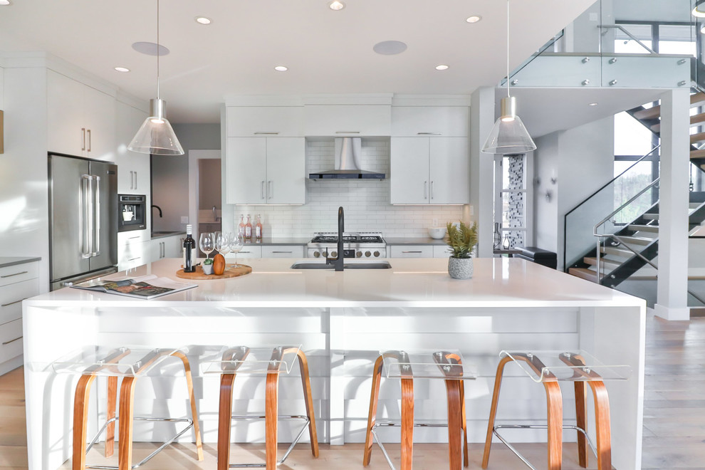 This is an example of a mid-sized contemporary l-shaped eat-in kitchen in Other with a single-bowl sink, flat-panel cabinets, white cabinets, quartz benchtops, white splashback, stainless steel appliances and with island.