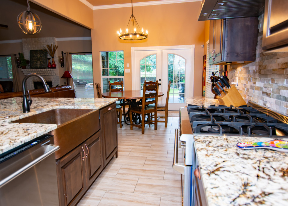 Transitional porcelain tile and beige floor kitchen photo in Austin with a farmhouse sink, raised-panel cabinets, dark wood cabinets, granite countertops, stone tile backsplash, stainless steel appliances and an island