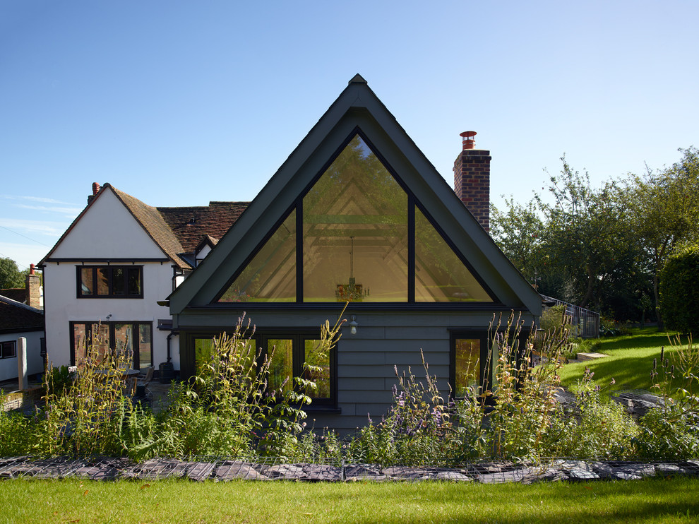 Photo of a mid-sized traditional one-storey grey house exterior in Hertfordshire with wood siding and a gable roof.