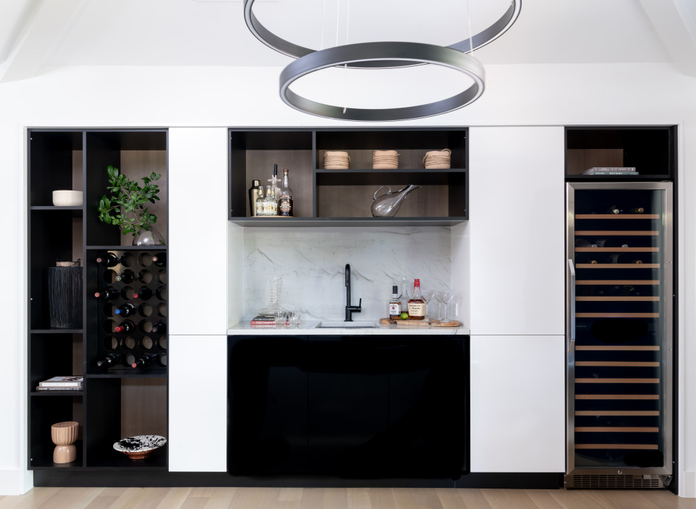 Contemporary home bar in Dallas with an undermount sink, flat-panel cabinets, black cabinets, white splashback and light hardwood floors.