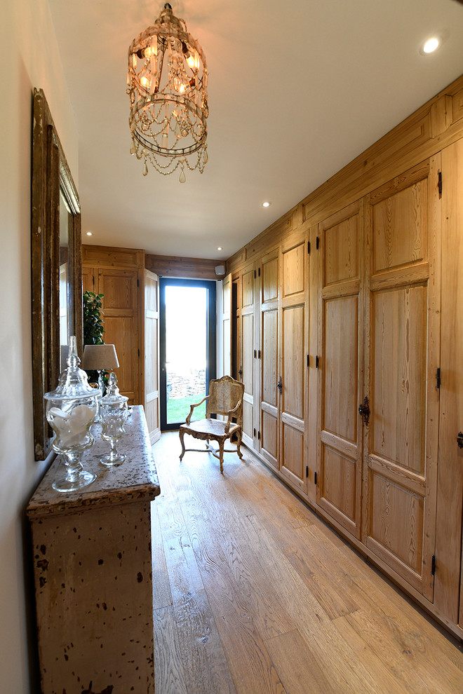 Inspiration for a traditional women's walk-in wardrobe in Marseille with raised-panel cabinets, medium wood cabinets, light hardwood floors and beige floor.