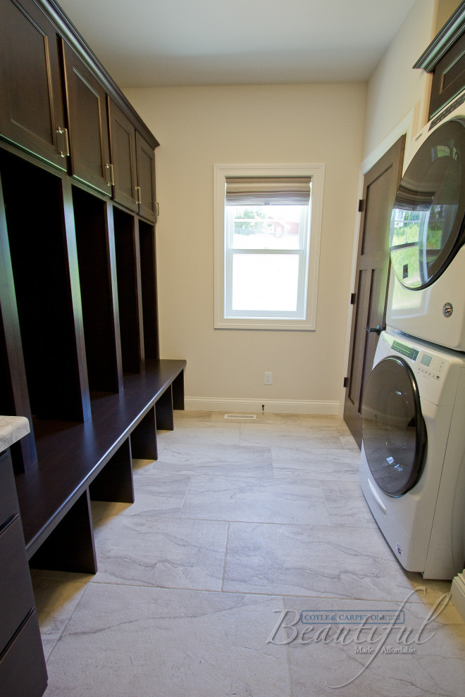 This is an example of a galley utility room in Other with shaker cabinets, brown cabinets, laminate benchtops, ceramic floors and a stacked washer and dryer.