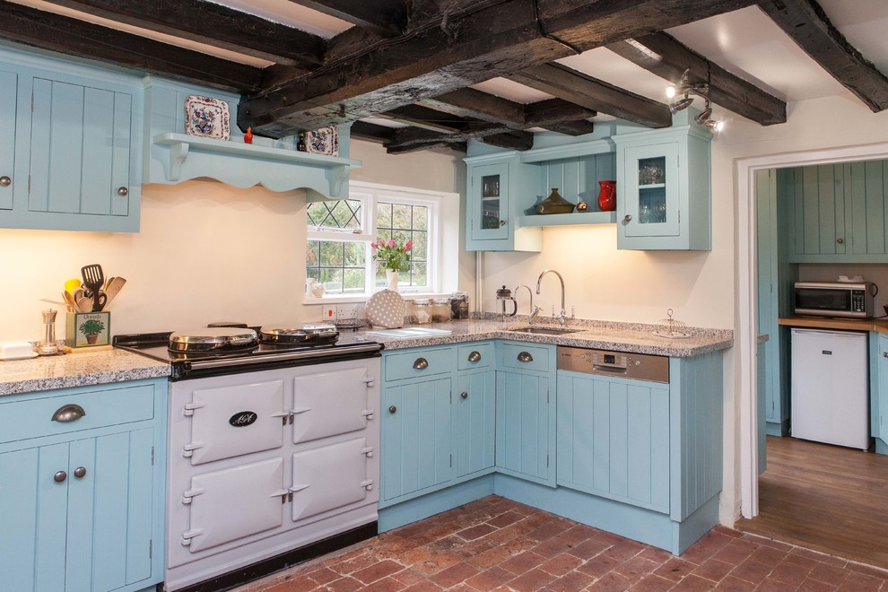 This is an example of a country separate kitchen in Other with an undermount sink, blue cabinets, beige splashback, white appliances and brick floors.