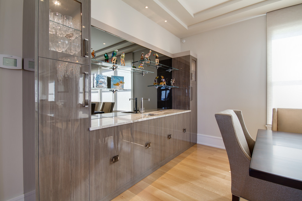 Photo of a mid-sized contemporary single-wall wet bar in Philadelphia with an undermount sink, flat-panel cabinets, medium wood cabinets, mirror splashback, light hardwood floors and quartzite benchtops.