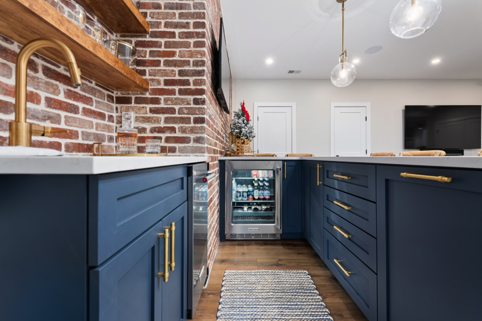 Design ideas for a mid-sized country l-shaped wet bar in Philadelphia with a drop-in sink, shaker cabinets, blue cabinets, quartzite benchtops, red splashback, brick splashback, dark hardwood floors, brown floor and grey benchtop.