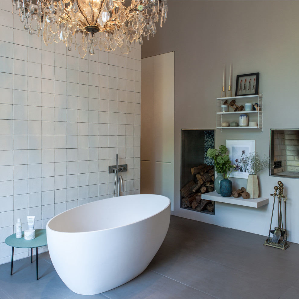 Photo of a large contemporary master bathroom in Hamburg with flat-panel cabinets, light wood cabinets, a freestanding tub, a curbless shower, a wall-mount toilet, white tile, limestone, beige walls, ceramic floors, a drop-in sink, solid surface benchtops, grey floor, an open shower and brown benchtops.