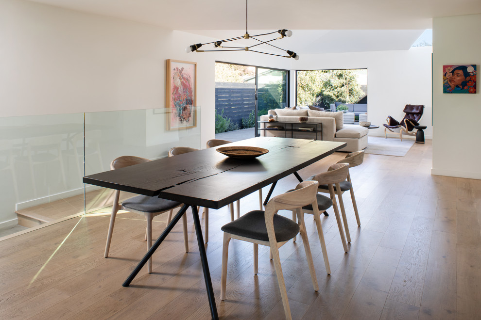 This is an example of a large modern open plan dining in San Francisco with white walls, light hardwood floors and beige floor.