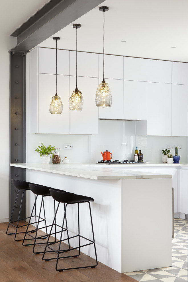 Photo of a contemporary u-shaped open plan kitchen in London with flat-panel cabinets, white cabinets, white splashback and a peninsula.