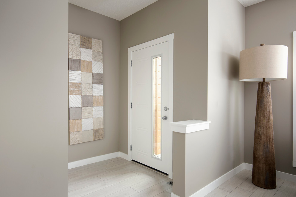 This is an example of a small contemporary mudroom in Calgary with beige walls, a pivot front door, a white front door and light hardwood floors.